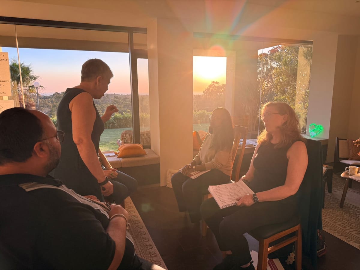 Participants in a coaching practice session as the sun sets over the hills